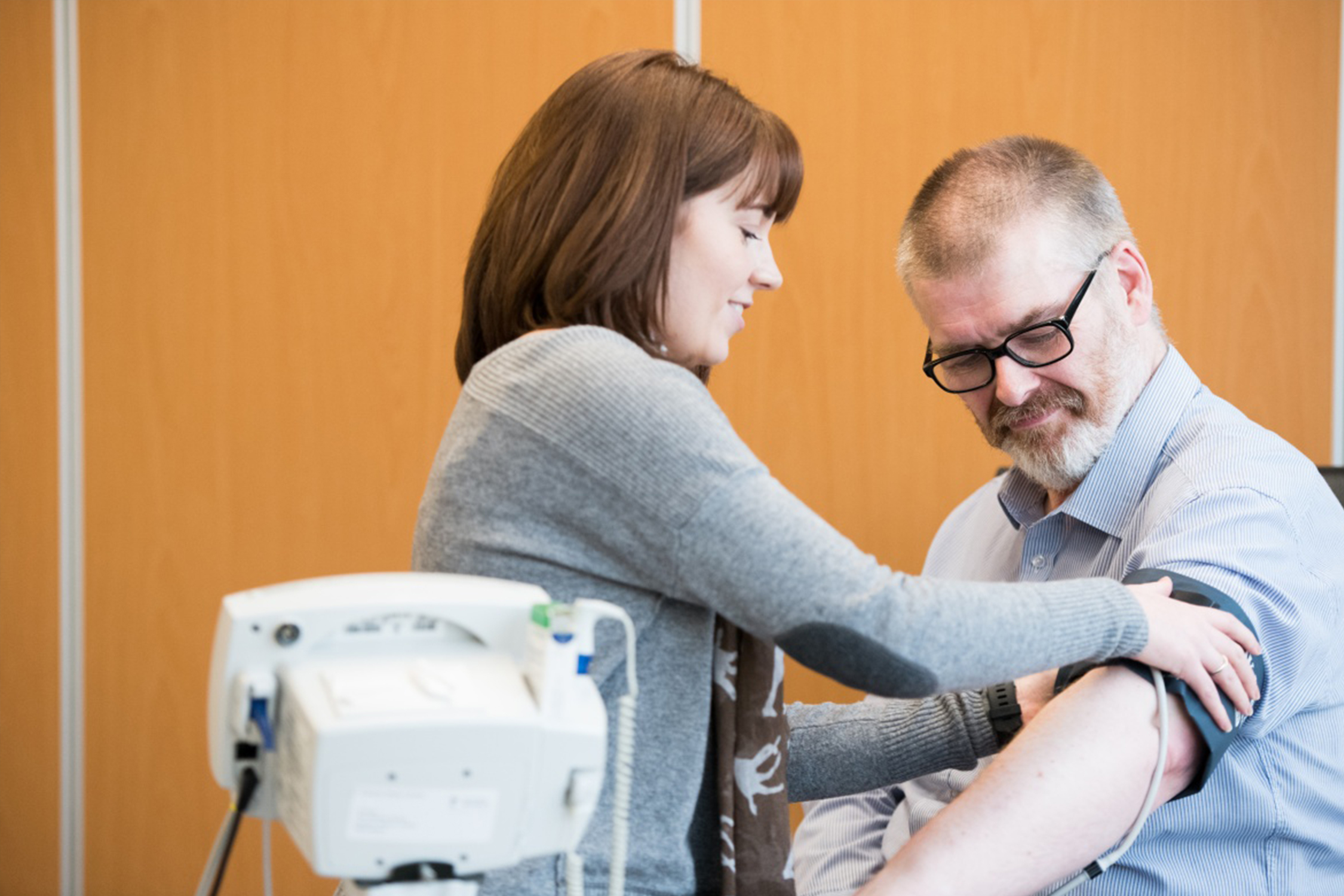 Postgraduate student putting blood pressure monitor on man