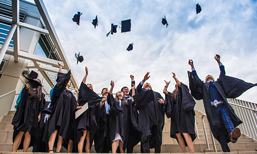 Mixed group of graduates throwing their hats in the air