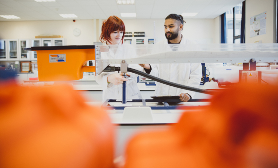 Two students wearing white coats working in laboratory