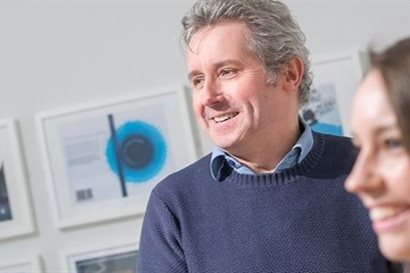 Man and woman smiling in front of gallery of artwork