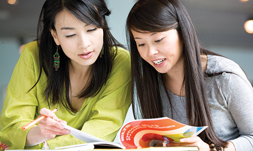 Two students reading an IELTS brochure