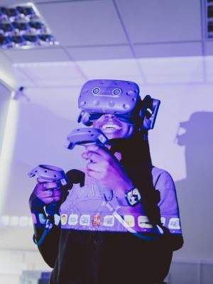 A man standing in a room surrounded by plants, talking to another person