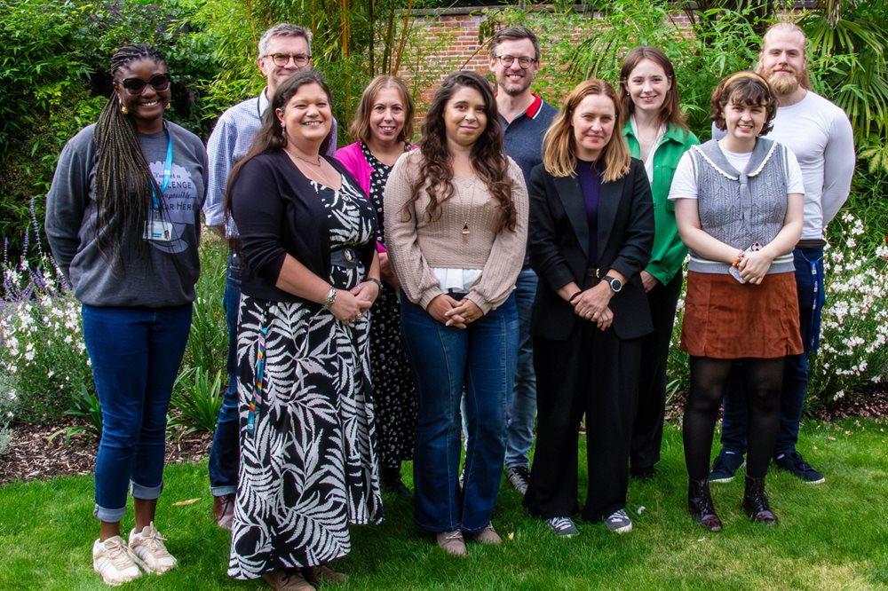 Group of ten men and women smiling in front of a panelled wall