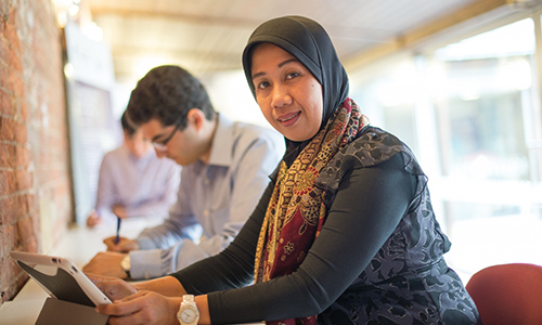 Postgraduate student working on computer while looking at camera