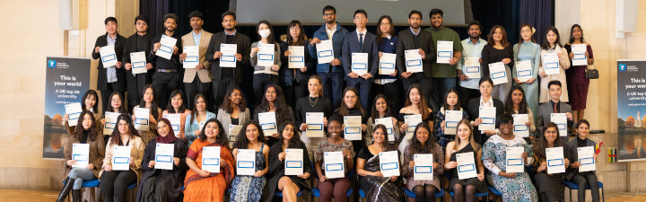 Group of scholarship winners standing in a line holding certificates