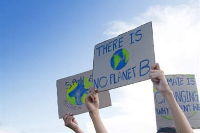 Three handheld cardboard banners protesting climate change