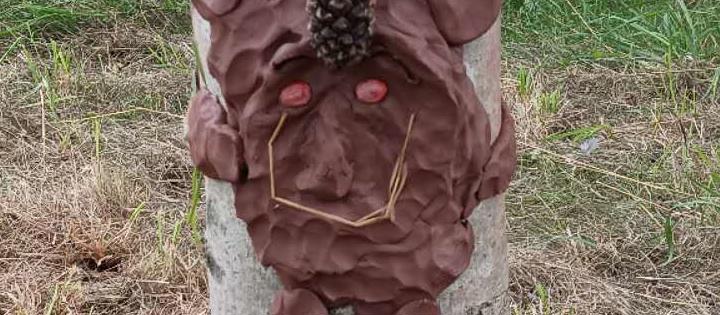 Photograph of a clay face sculpture on a tree