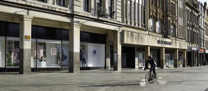 Man cycling down an empty high-street 