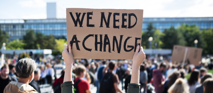 Hands holding up a we need a change sign