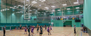 Students playing basketball in a sports hall