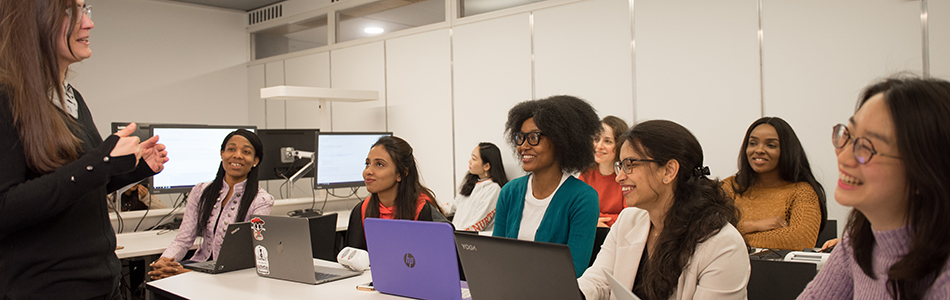 A group of international students in a classroom, listening to their lecturer