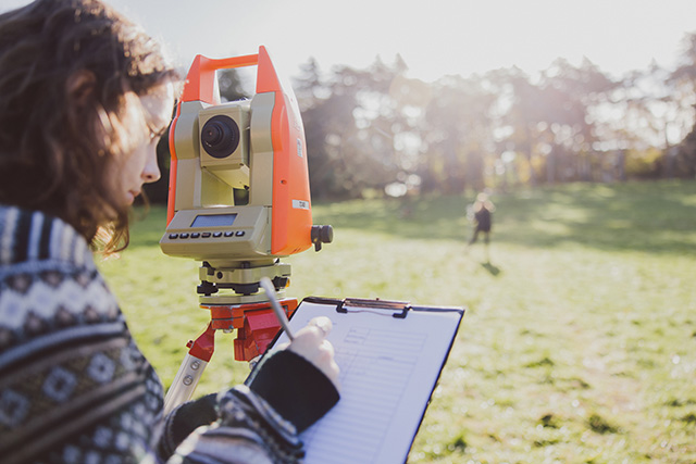 Undergraduate students using surveying equipment on the Downs