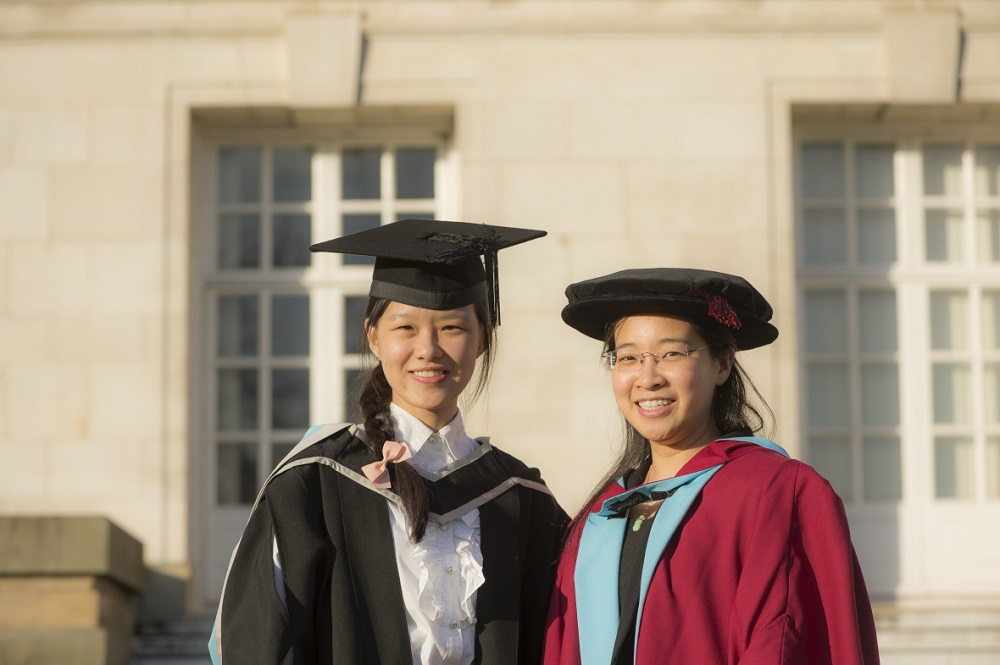 Two female students wearing graduation caps and gowns
