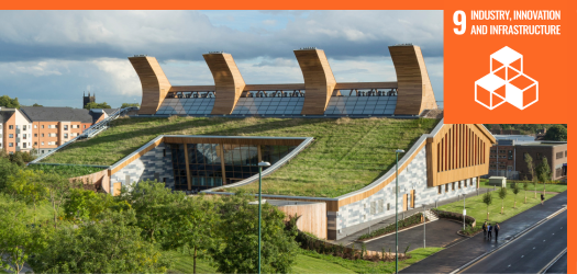 Large building with plants on the roof, surrounded by trees