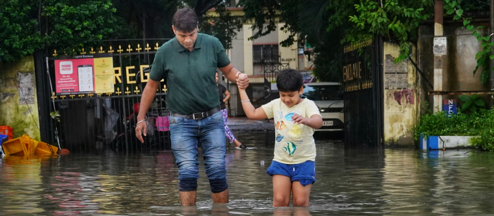 Father and son wading through flooded street