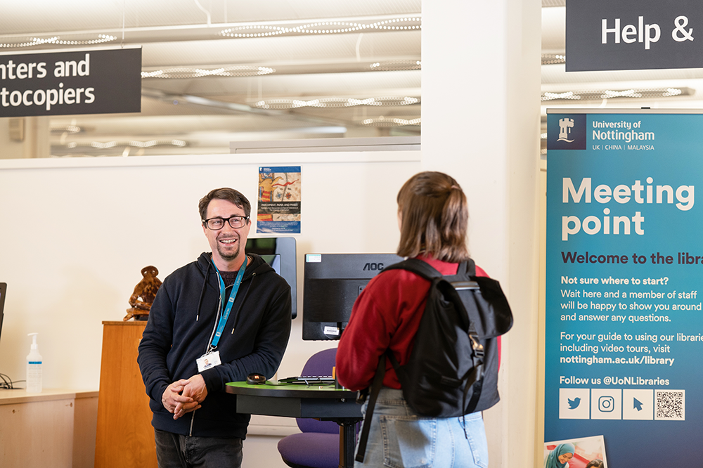 Member of staff helping a student in Hallward Library