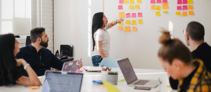 Photo of person talking to a group in front of a white board
