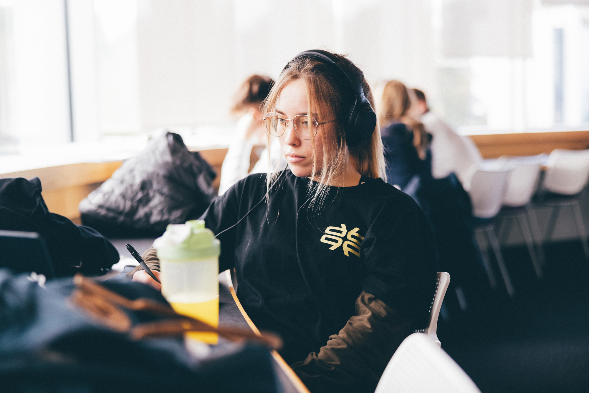 A female student studying in the library with headphones on
