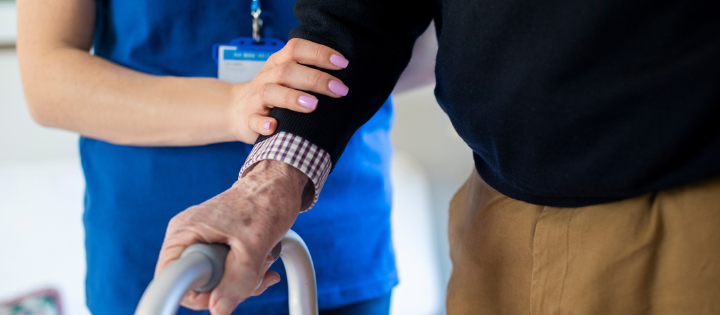 Nurse supporting an elderly man holding a walking frame