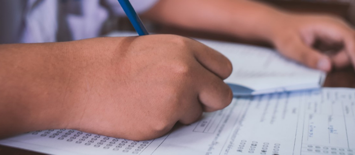 A school child writing, holding a pencil