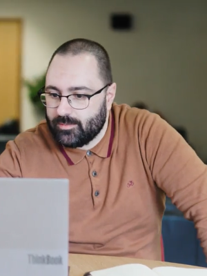 A man standing smiling infront of a wall with the Innovate UK logo on